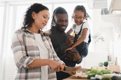 mother cooking meal while dad and adoptive daughter watch to demonstrate Openness in Adoption