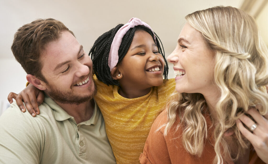 Family diversity and adoption with a foster mother, father and girl bonding in the living room of t.