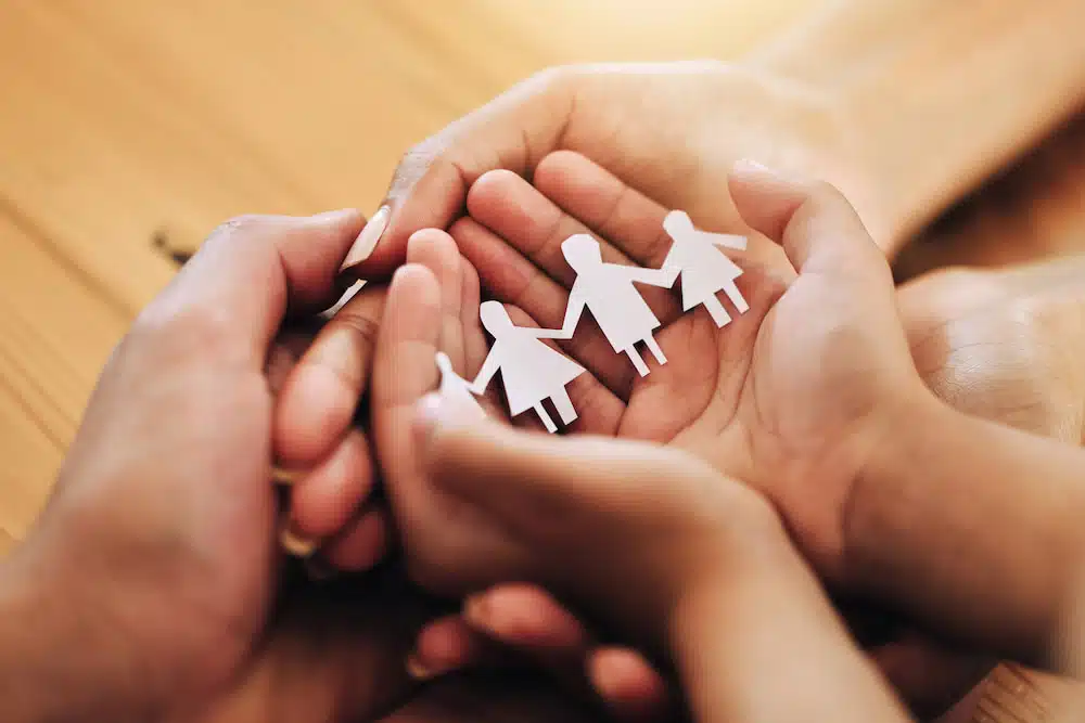 papercut origami of a family in a hand of a parent and an adopted kid symbolizing foster care