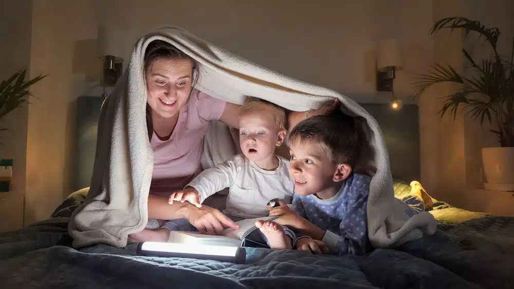 happy family lying on bed at night and reading