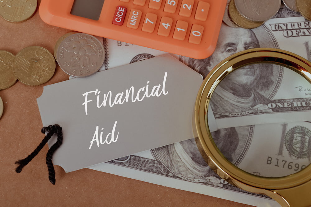 magnifying glass, calculator, and coin and paper money on financial aid for adoption