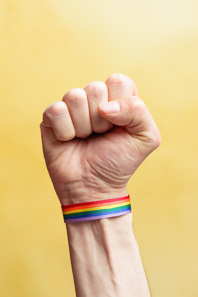 Raised fist with LGBT rainbow flag bracelet in navigating through lgbt families discrimination
