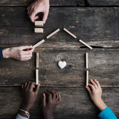 Hands forming a house with building blocks