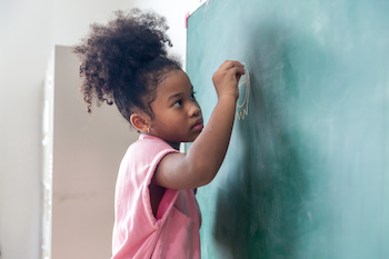 Educational Goals and Values of adoptive parents to their kid: little girl writing on a blackboard using a chalk