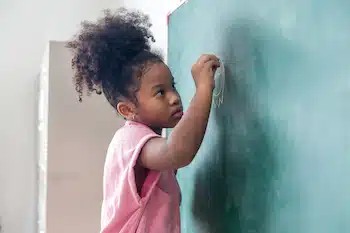 a child writing on the chalk board