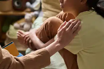 a hand tapping the shoulder of child to comfort