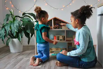 two children playing with a doll house