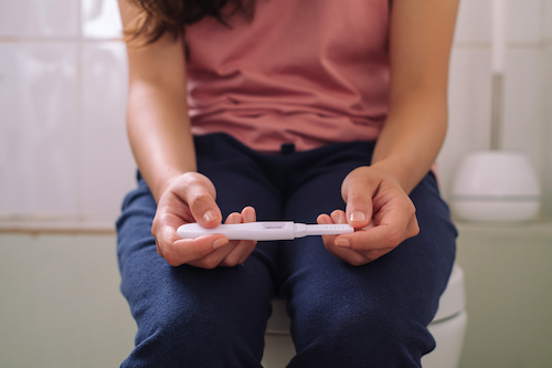 woman worried about unexpected pregnancy test result in the bathroom not knowing to whom to tell 