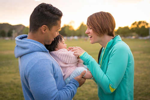 couple playing with their  newborn foster baby in the park