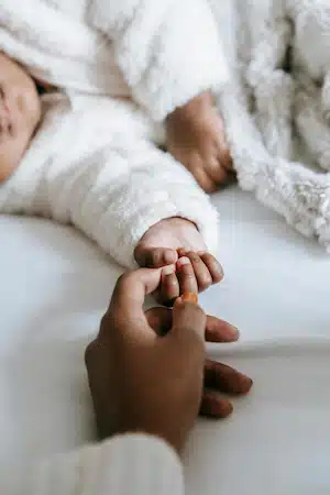 mother holding her baby's hand while sleeping