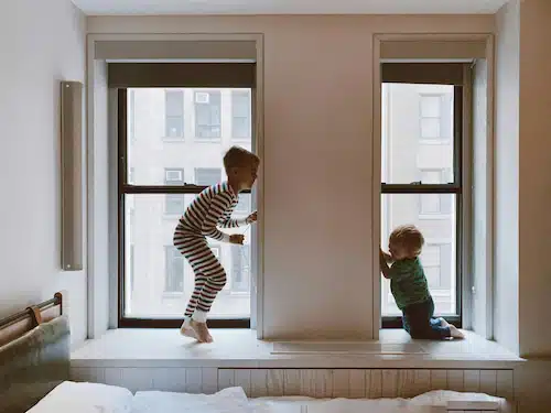 siblings playing on the windows of the apartment