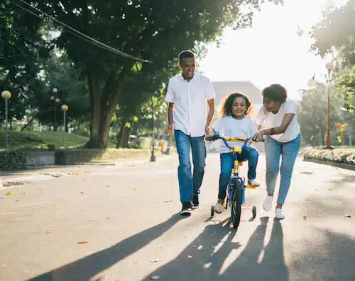 parents teaching their adoptive daughter how to ride a bike