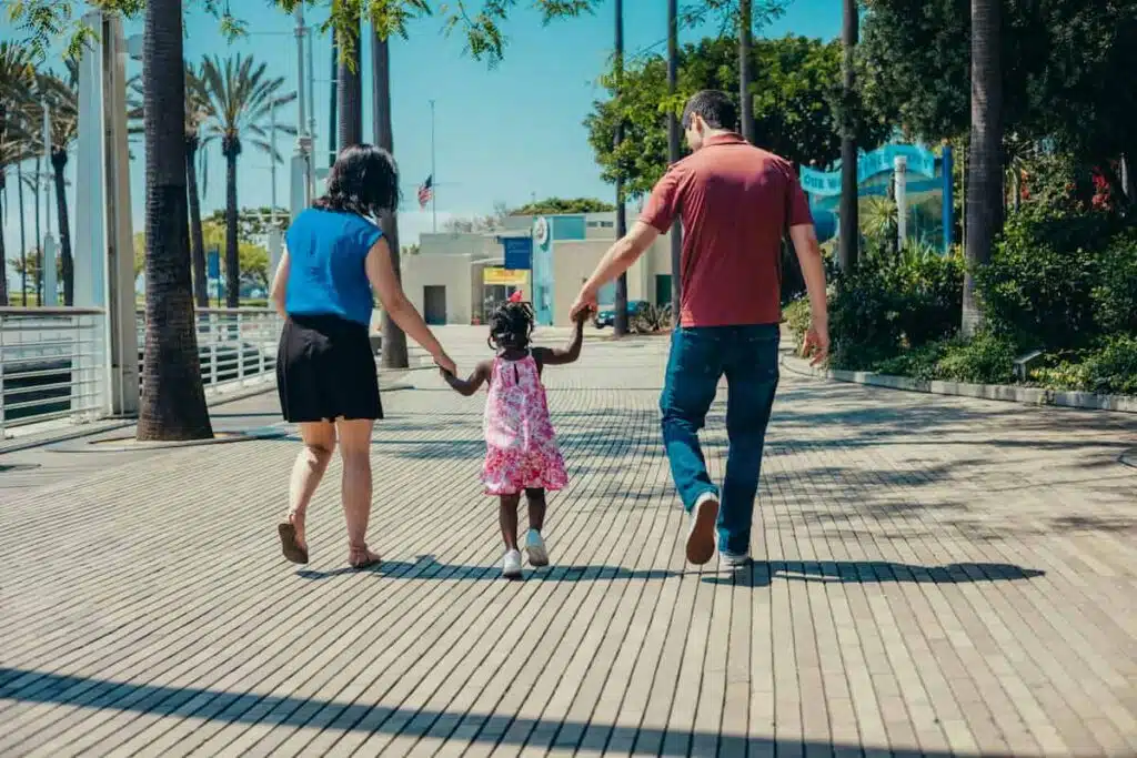 Man in Red Tank Top and Blue Denim Shorts Holding Girl in Pink Dress