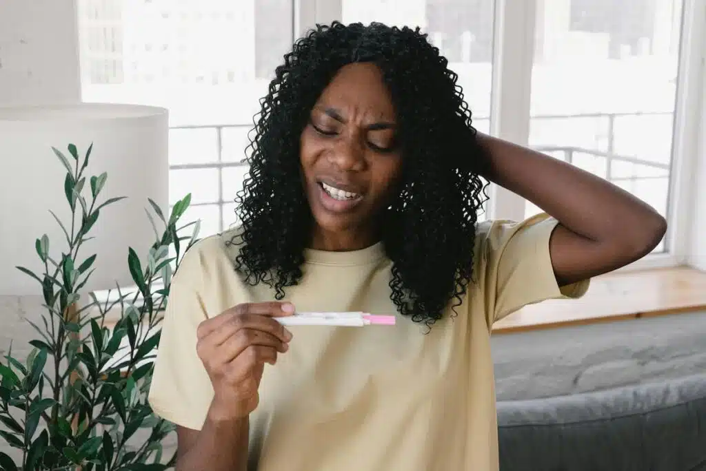 Upset black woman with pregnancy test