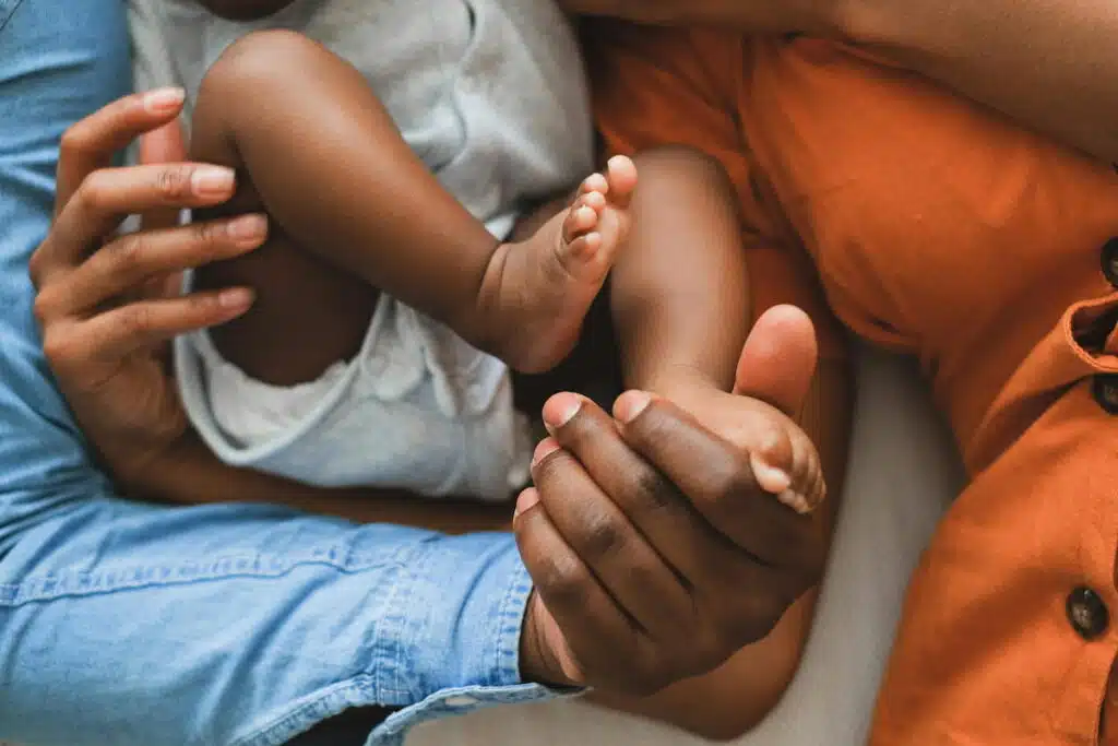 A Person in Blue Denim Jeans Holding Baby's Foot