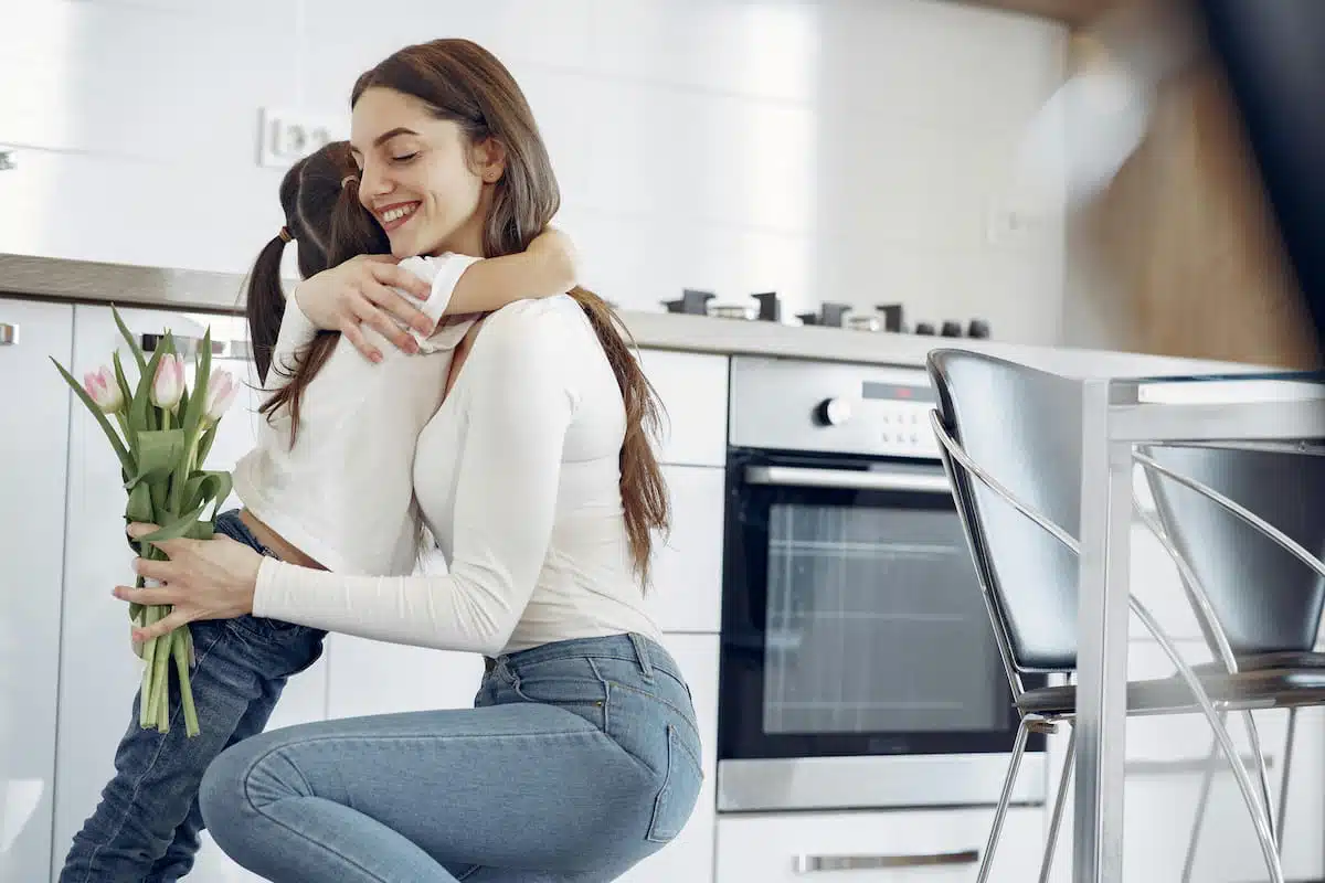 Photo of Woman Hugging Her Child While Holding Tulips