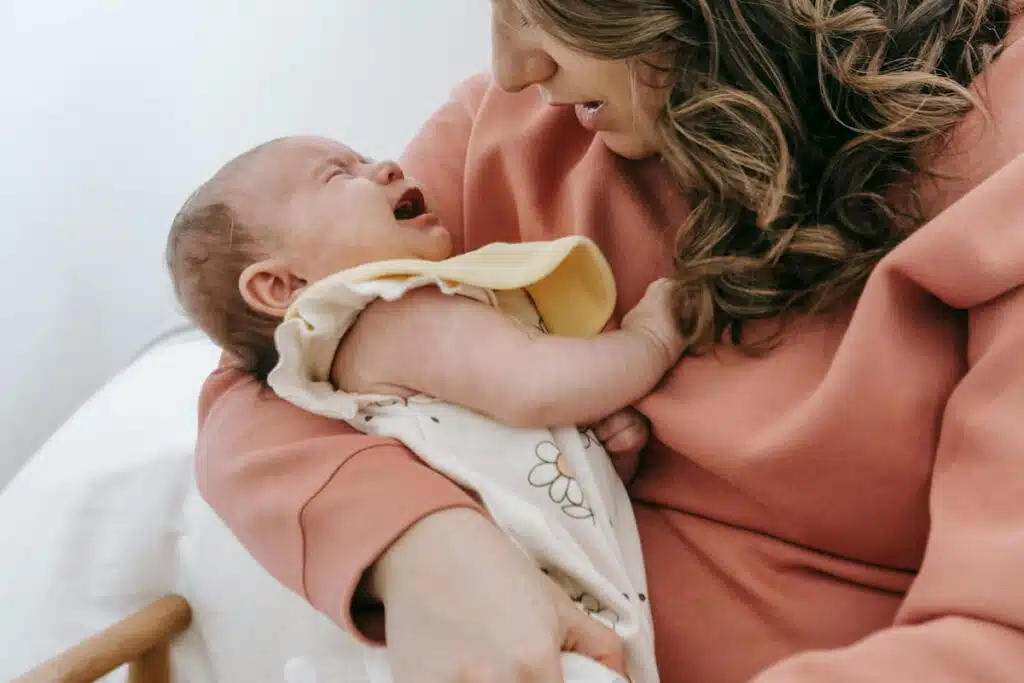 Unrecognizable-mother-with-crying-baby-in-arms