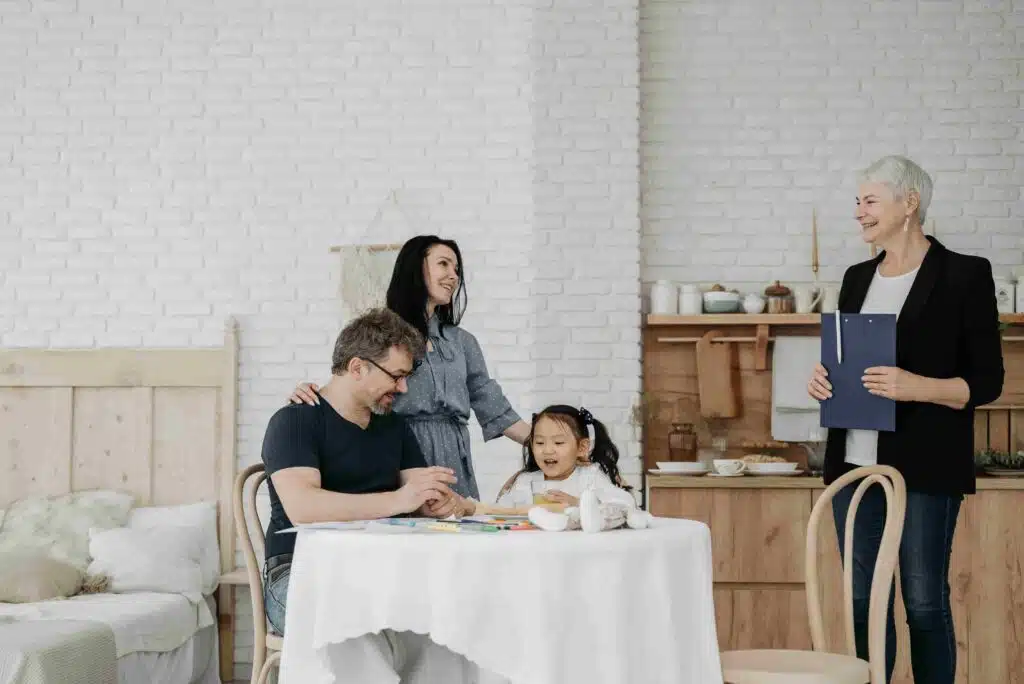 A family gathered around a table in a room, representing the warmth of Open Arms Adoptions.