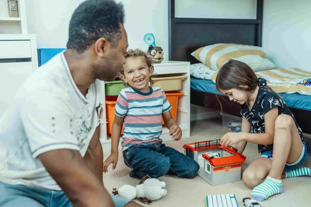 A man with two children as they play with toys, emphasizing the joy of family connections.
